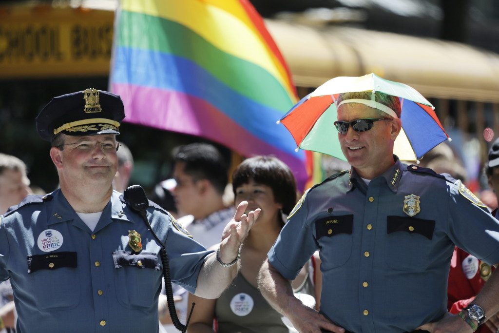 Seattle interim Police Chief Jim Pugel, right, wears a rainbow umbrella hat as he stands with Assistant Chief Dick Reed before beginning to march with other police officers in the Gay Pride parade Sunday, June 30, 2013, in Seattle. (AP Photo/Elaine Thompson)