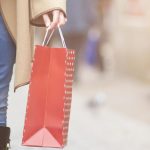 Woman walking in street with gift bag, close up.