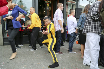 Casey Bui, co-president of the board of trustees of the Wing Luke, dresses in the classic suit of Bruce Lee and performs a technique of Kung Fu amid the crowd in front of the museum on Oct 4. Photo by Senhao Liu. Casey Bui, co-president of the board of trustees of the Wing Luke, dresses in the classic suit of Bruce Lee and performs a technique of Kung Fu amid the crowd in front of the museum on Oct 4. Photo by Senhao Liu.